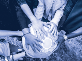 Various hands on a globe featuring multiple races