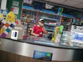 Worker at counter of Guatemalan convenience store selling tobacco products