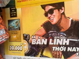 Printed signage advertising cigarettes, featuring a man with sunglasses on a motorcycle, posted at a retailer in Ha Noi