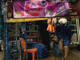 A man exits a tobacco retailer in Indonesia. A banner advertising tobacco is prominently displayed
