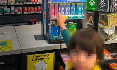 A child with their face blurred reaches their outstretched arm towards a countertop tobacco product display at a retailer in Mexico