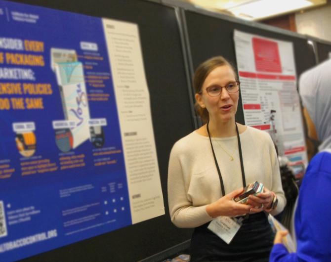 A woman in a white top speaks with a woman in a blue top and white hijab at an academic conference